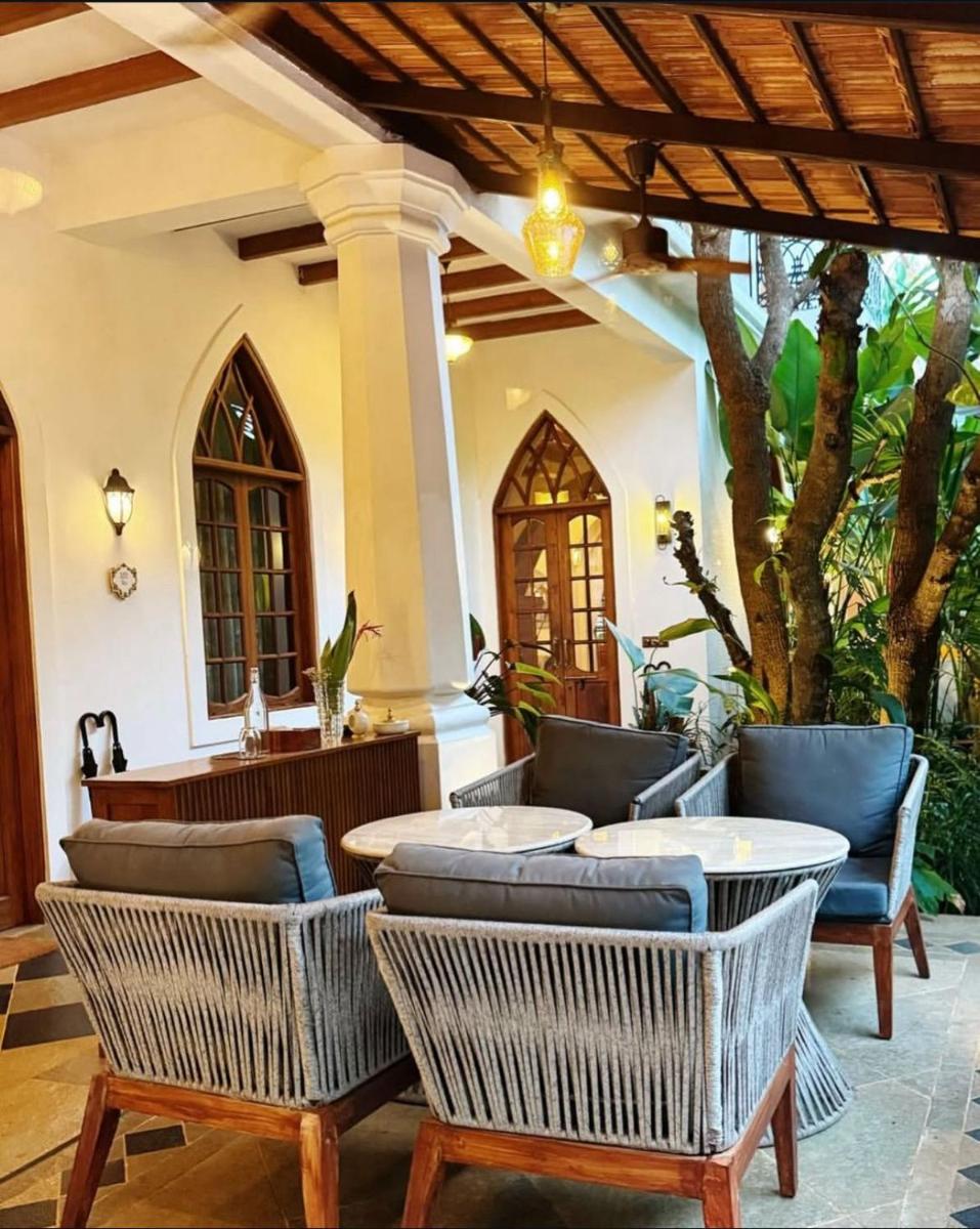 a patio with wicker chairs and tables on a house at The Postcard Saligao in Calangute