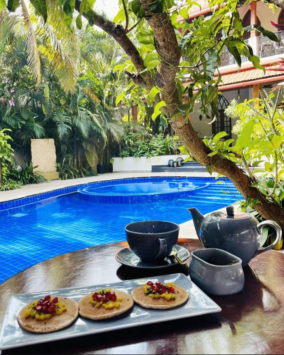 a tray with food on a table next to a pool at The Postcard Saligao in Calangute