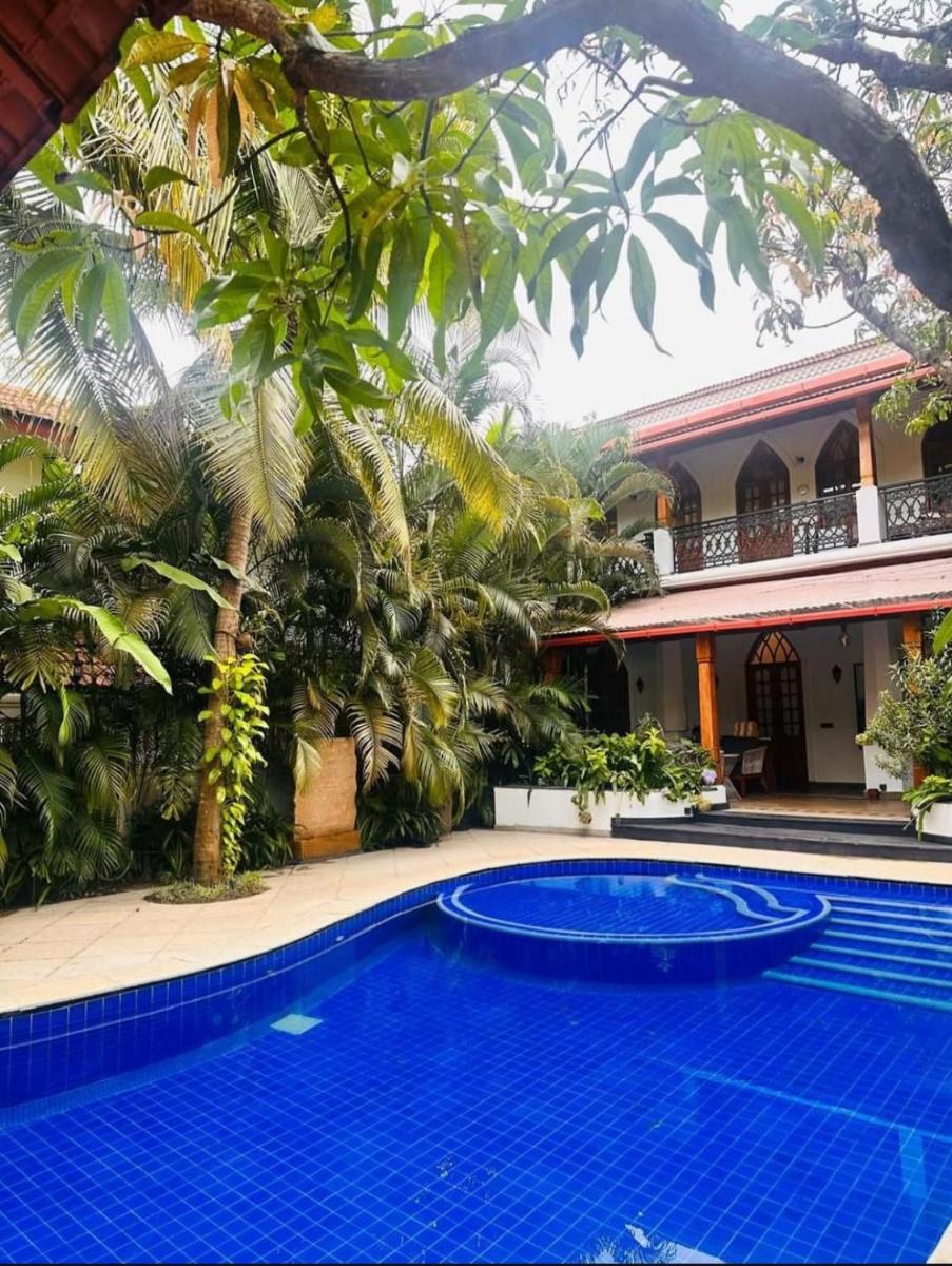 a large blue swimming pool in front of a house at The Postcard Saligao in Calangute