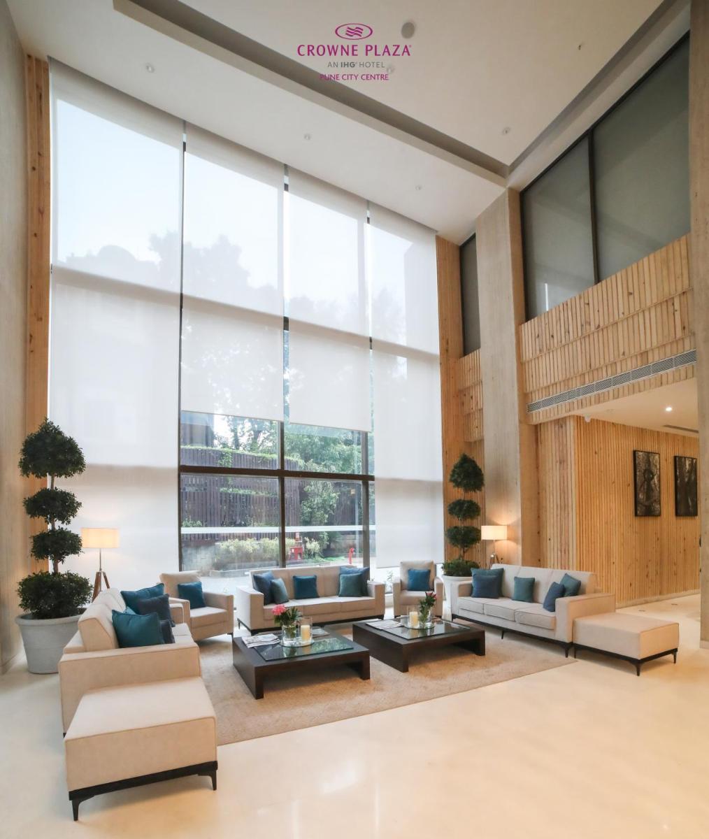 a lobby with couches and tables in front of a large window at Crowne Plaza Pune City Centre by IHG in Pune