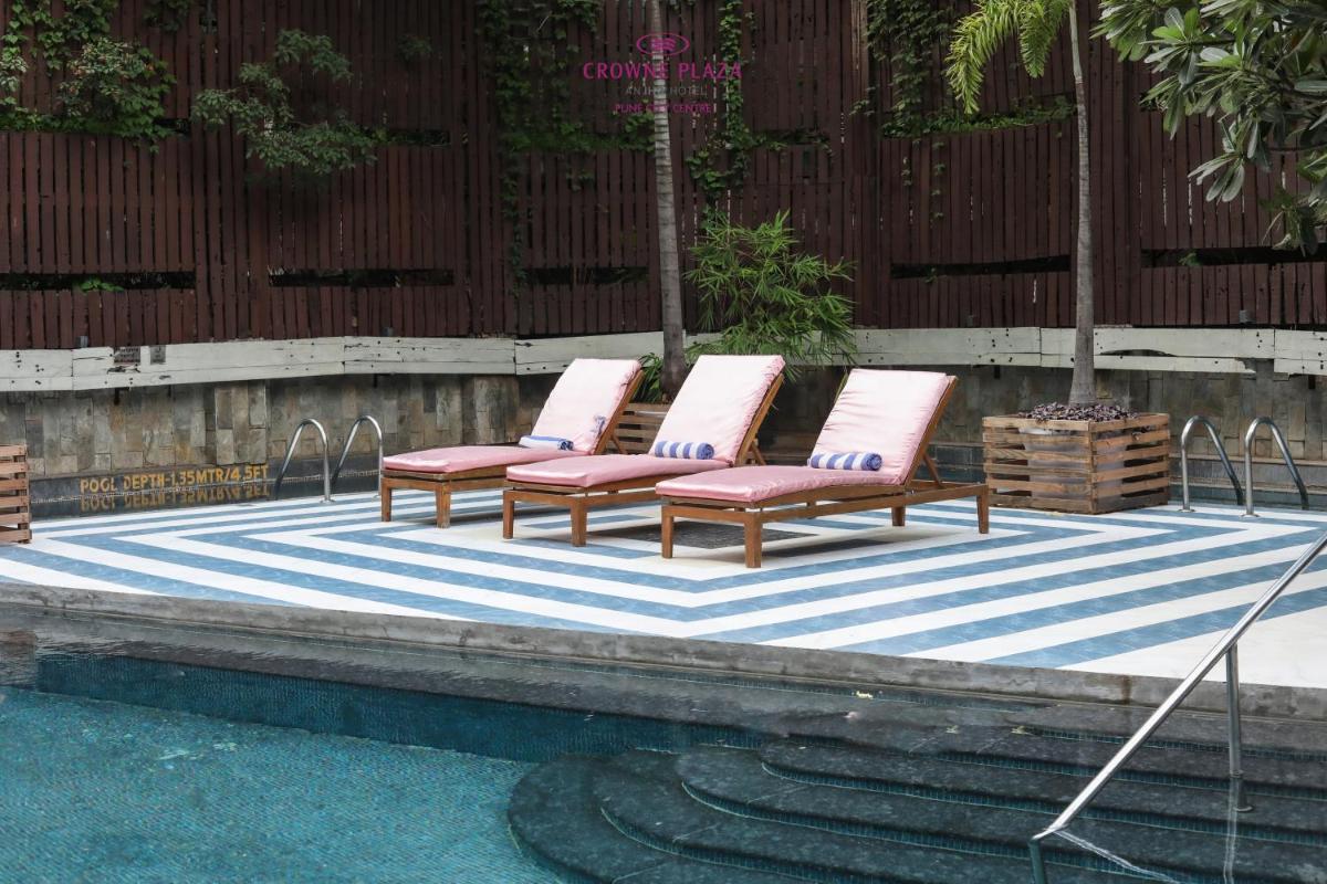 four lounge chairs with pink cushions sitting on a blue and white rug at Crowne Plaza Pune City Centre by IHG in Pune
