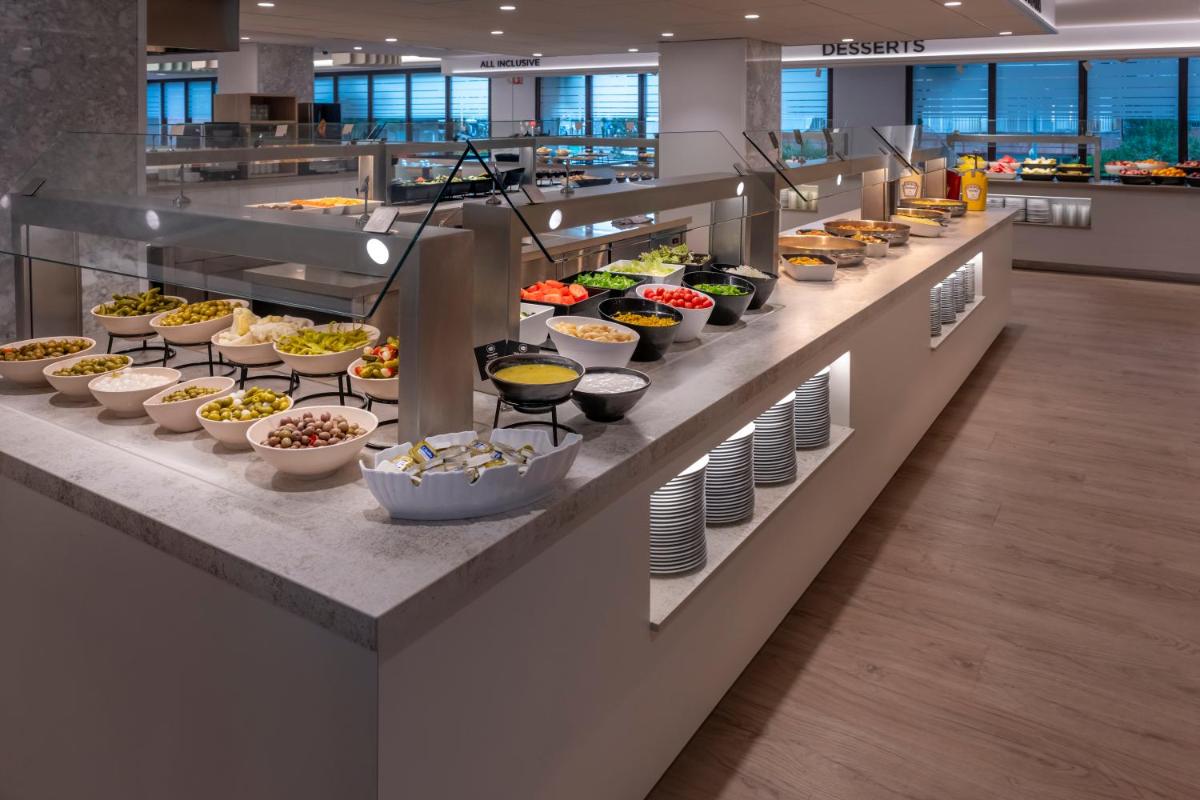 una línea de buffet con tazones de comida expuestos en GHT Oasis Park & Spa, en Lloret de Mar