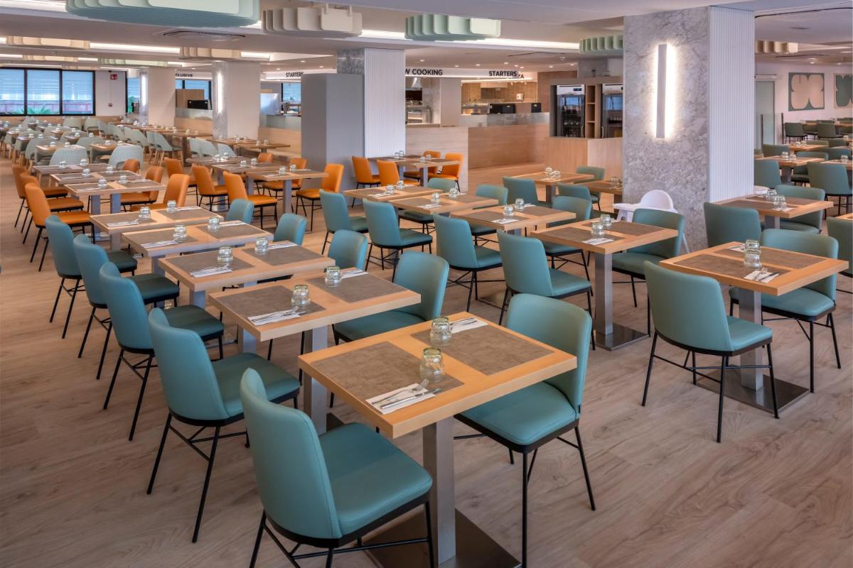Un comedor con mesas y sillas de madera. en GHT Oasis Park & Spa, en Lloret de Mar