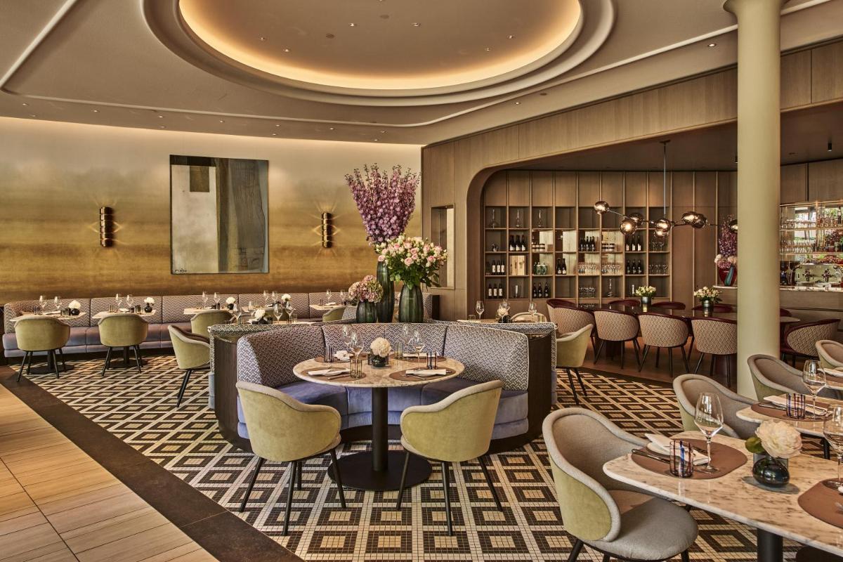 ein Restaurant mit Tischen und Stühlen und eine Bar in der Unterkunft The Fontenay Hamburg in Hamburg ein Restaurant mit Tischen und Stühlen und eine Bar in der Unterkunft The Fontenay Hamburg in Hamburg