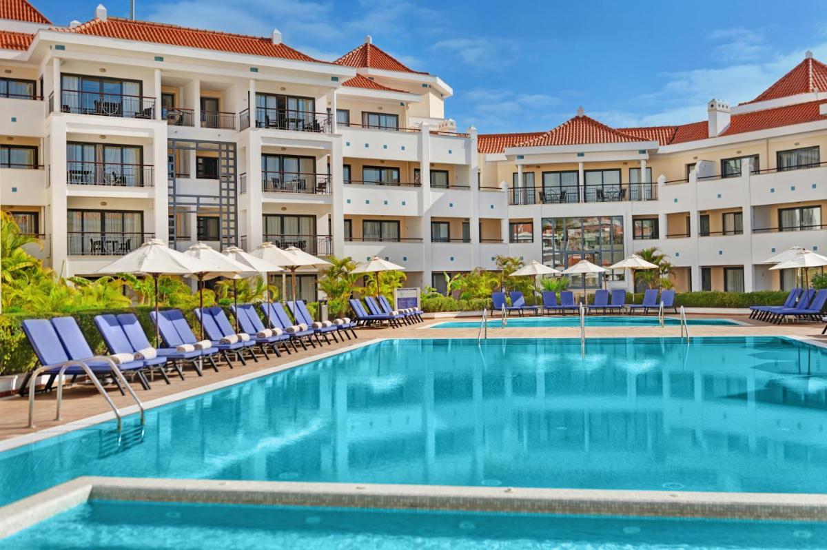 uma piscina em frente a um hotel com cadeiras e guarda-sóis em As Cascatas Golf Resort & Spa em Vilamoura