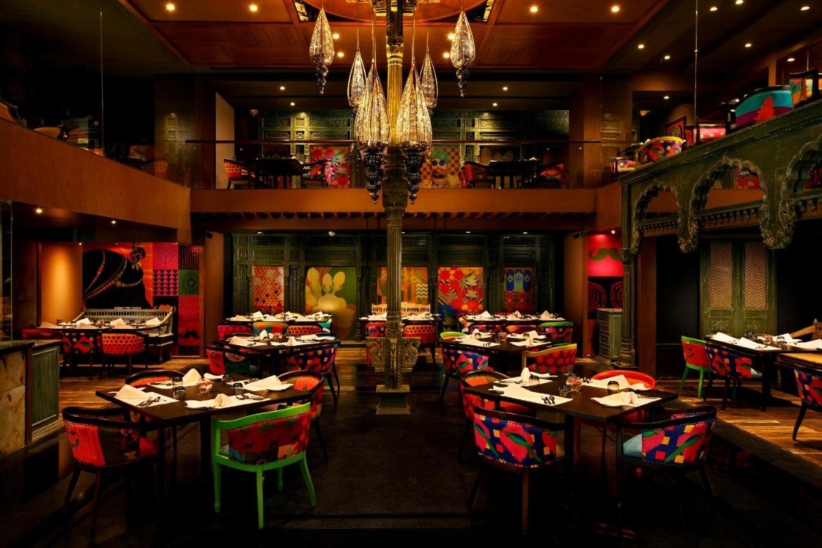 a restaurant with tables and chairs and a chandelier at Grand Chennai by GRT Hotels in Chennai