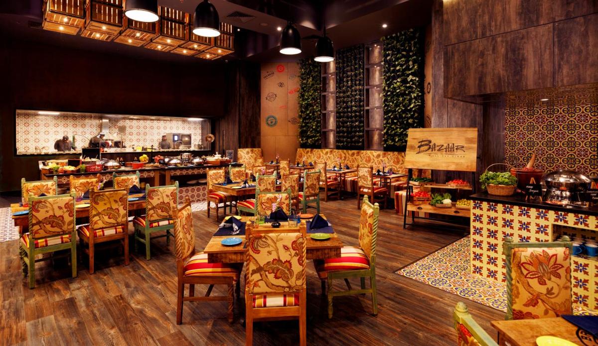 a restaurant with wooden tables and chairs and a counter at Grand Chennai by GRT Hotels in Chennai