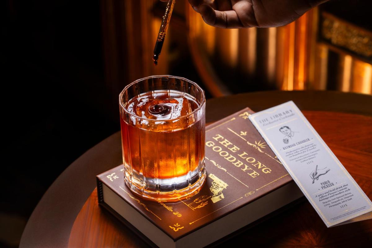 a drink in a glass on a book on a table at The Leela Palace New Delhi in New Delhi a drink in a glass on a book on a table at The Leela Palace New Delhi in New Delhi