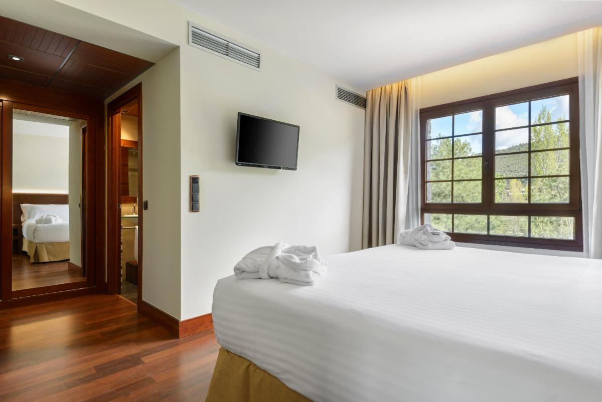 Un dormitorio con una gran cama blanca y una ventana. en Hotel & Spa Monasterio de Boltaña, en Boltaña