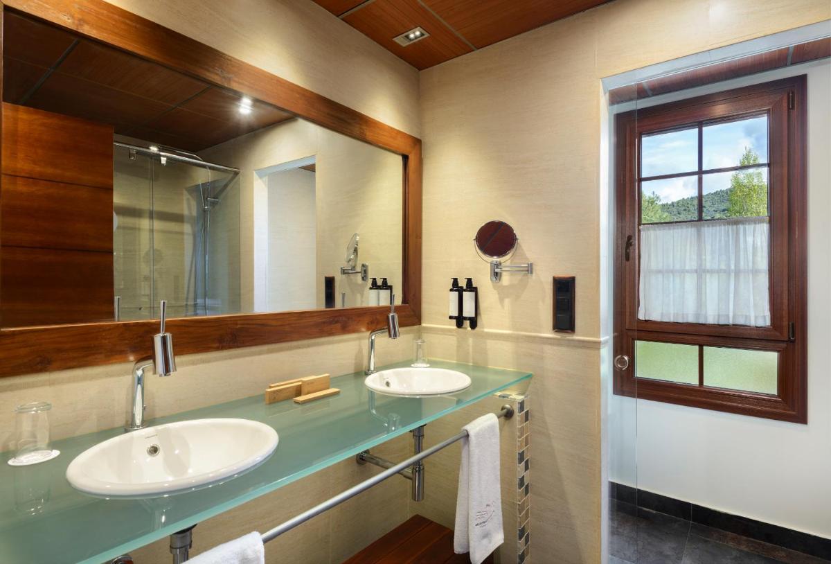 Un baño con dos lavabos y un espejo grande. en Hotel & Spa Monasterio de Boltaña, en Boltaña