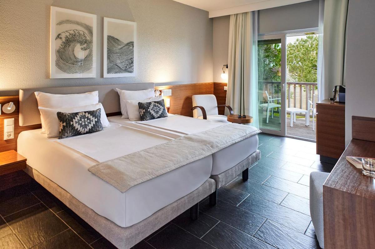 um quarto com uma cama grande e uma varanda em ROBINSON QUINTA DA RIA - All Inclusive em Vila Nova de Cacela