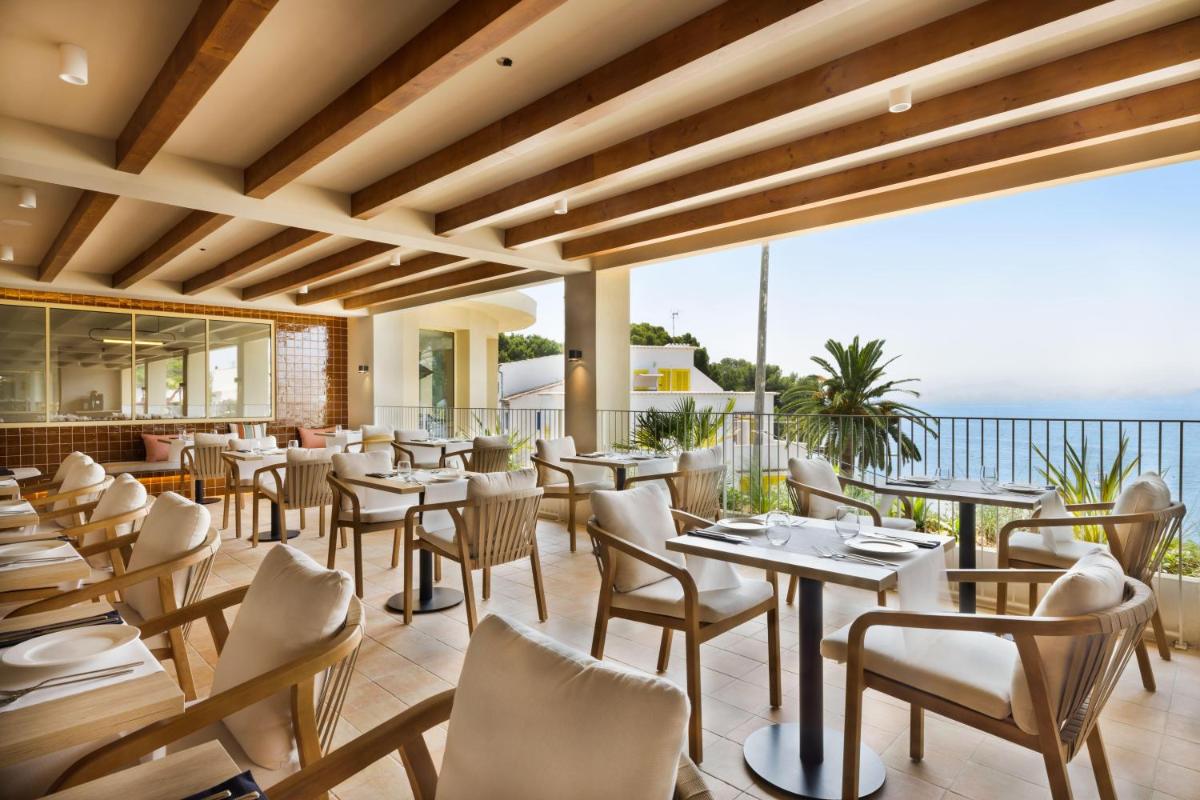 Un restaurante con mesas y sillas y el océano. en Inmood Aucanada 4 Sup, en Puerto de Alcudia
