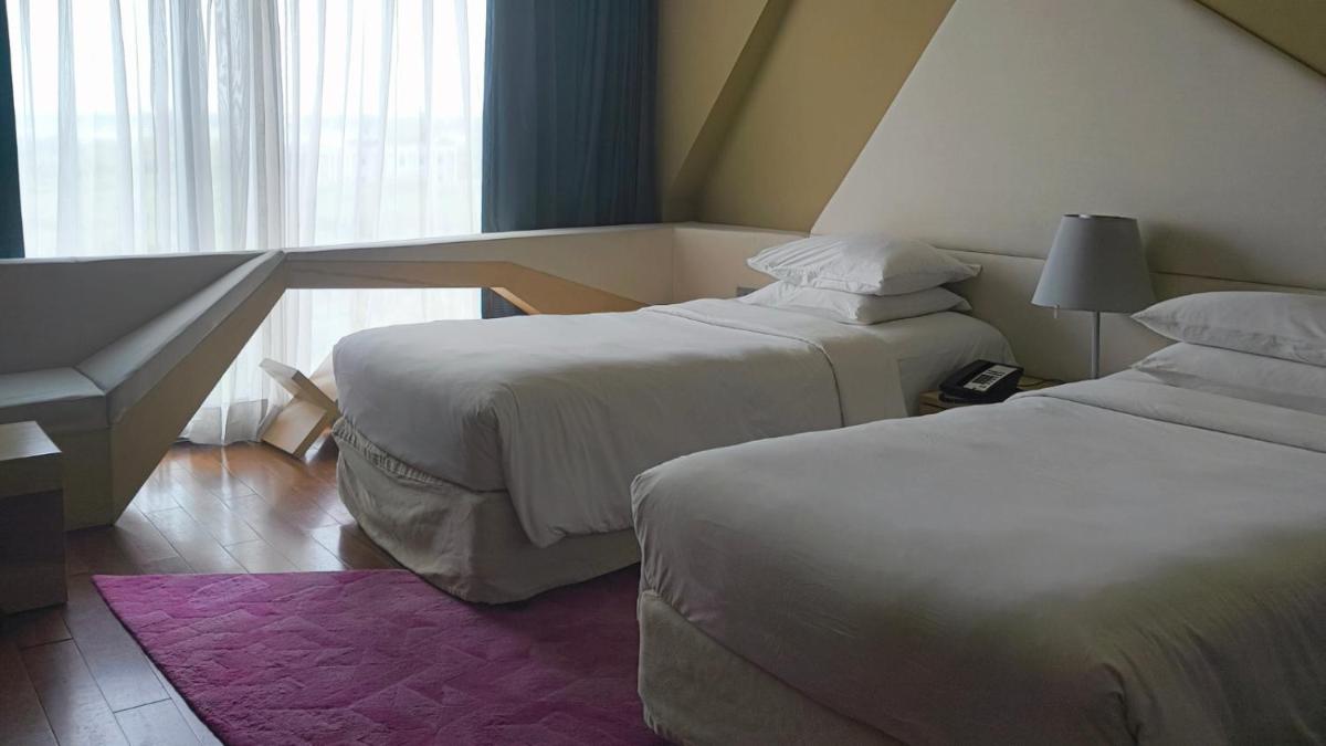 a hotel room with two beds and a window at Vivanta New Delhi, Dwarka in New Delhi a hotel room with two beds and a window at Vivanta New Delhi, Dwarka in New Delhi