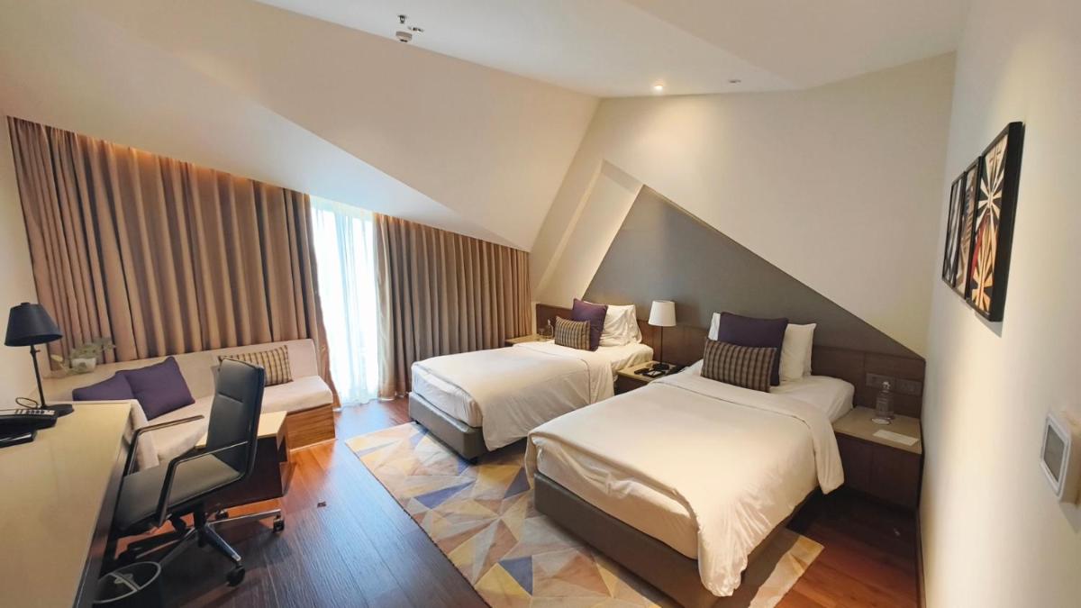 a hotel room with two beds and a desk at Vivanta New Delhi, Dwarka in New Delhi a hotel room with two beds and a desk at Vivanta New Delhi, Dwarka in New Delhi