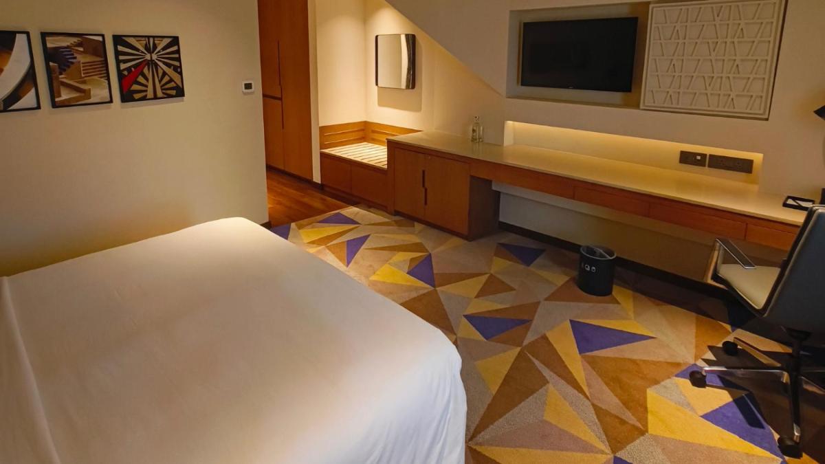 a room with a bed and a desk with a television at Vivanta New Delhi, Dwarka in New Delhi a room with a bed and a desk with a television at Vivanta New Delhi, Dwarka in New Delhi