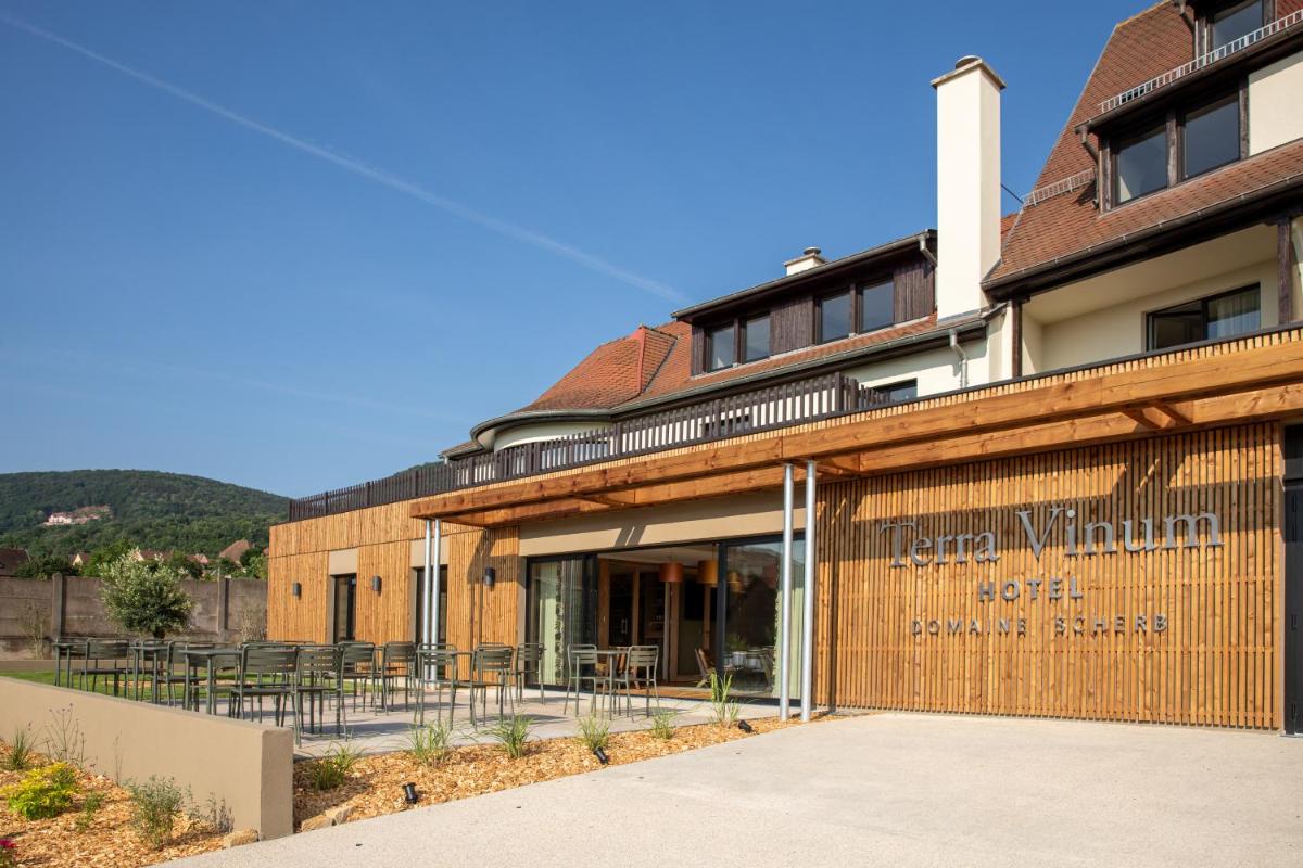 vue extérieure d'un bâtiment avec des tables et des chaises dans l'établissement Hôtel Terra Vinum, à Gueberschwihr