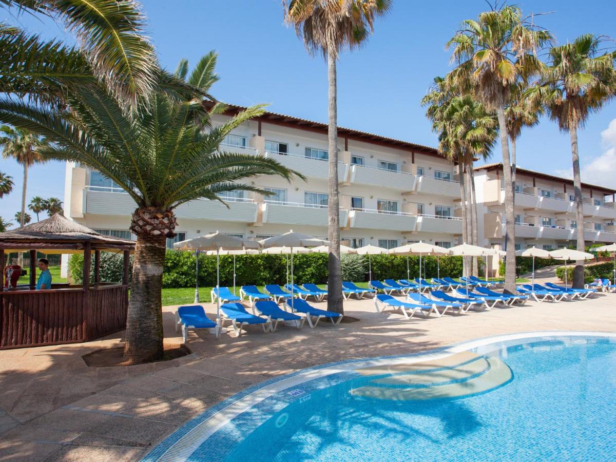 un hotel con sillas, piscina y palmeras en Grupotel Mallorca Mar, en Cala Bona