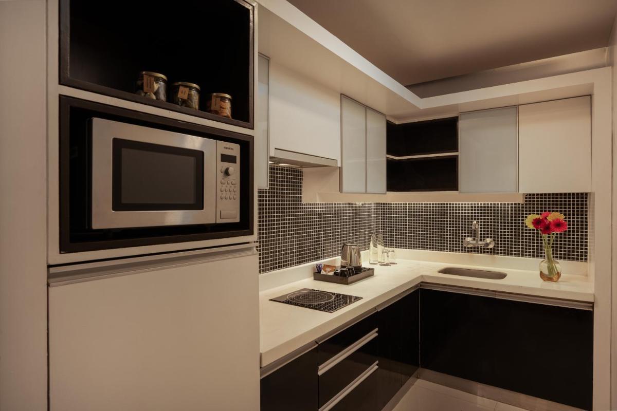 a kitchen with white cabinets and a microwave oven at Grand Mercure Bangalore - An Accor Brand in Bengaluru