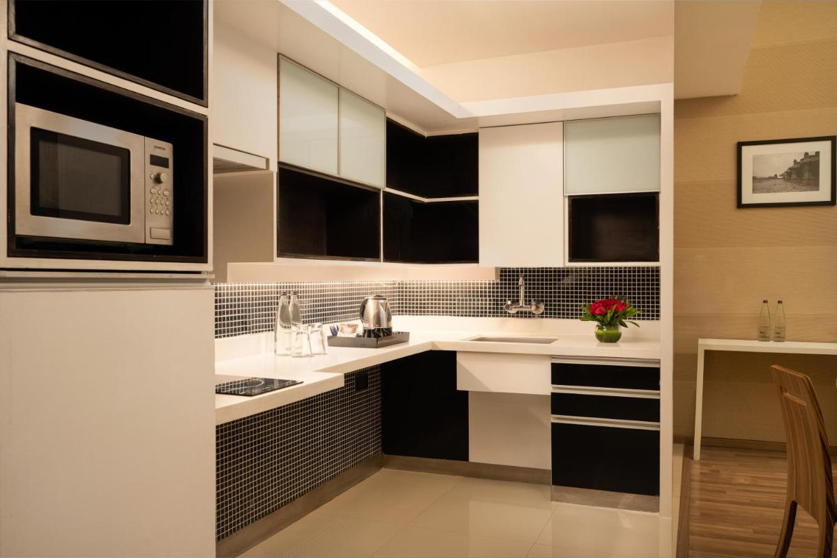 a kitchen with black and white cabinets and a microwave at Grand Mercure Bangalore - An Accor Brand in Bengaluru