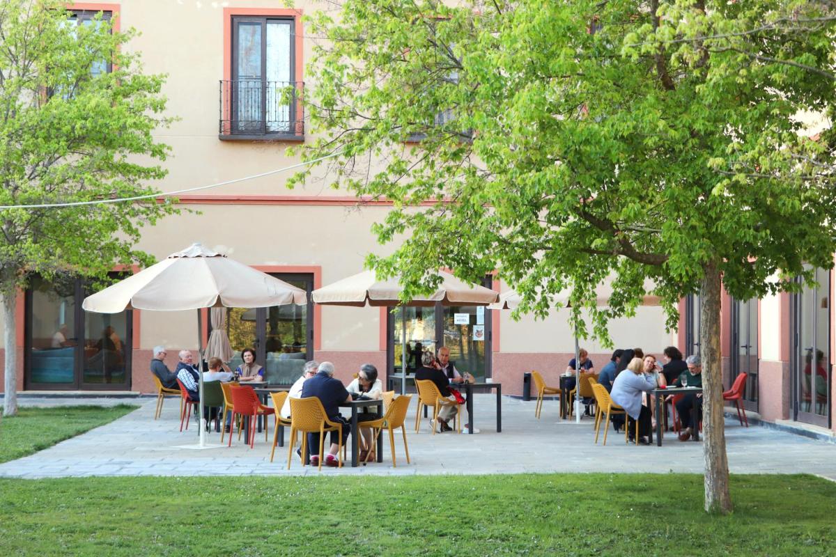 un grupo de personas sentadas en mesas fuera de un edificio en Hotel Real Balneario Carlos III, en Trillo