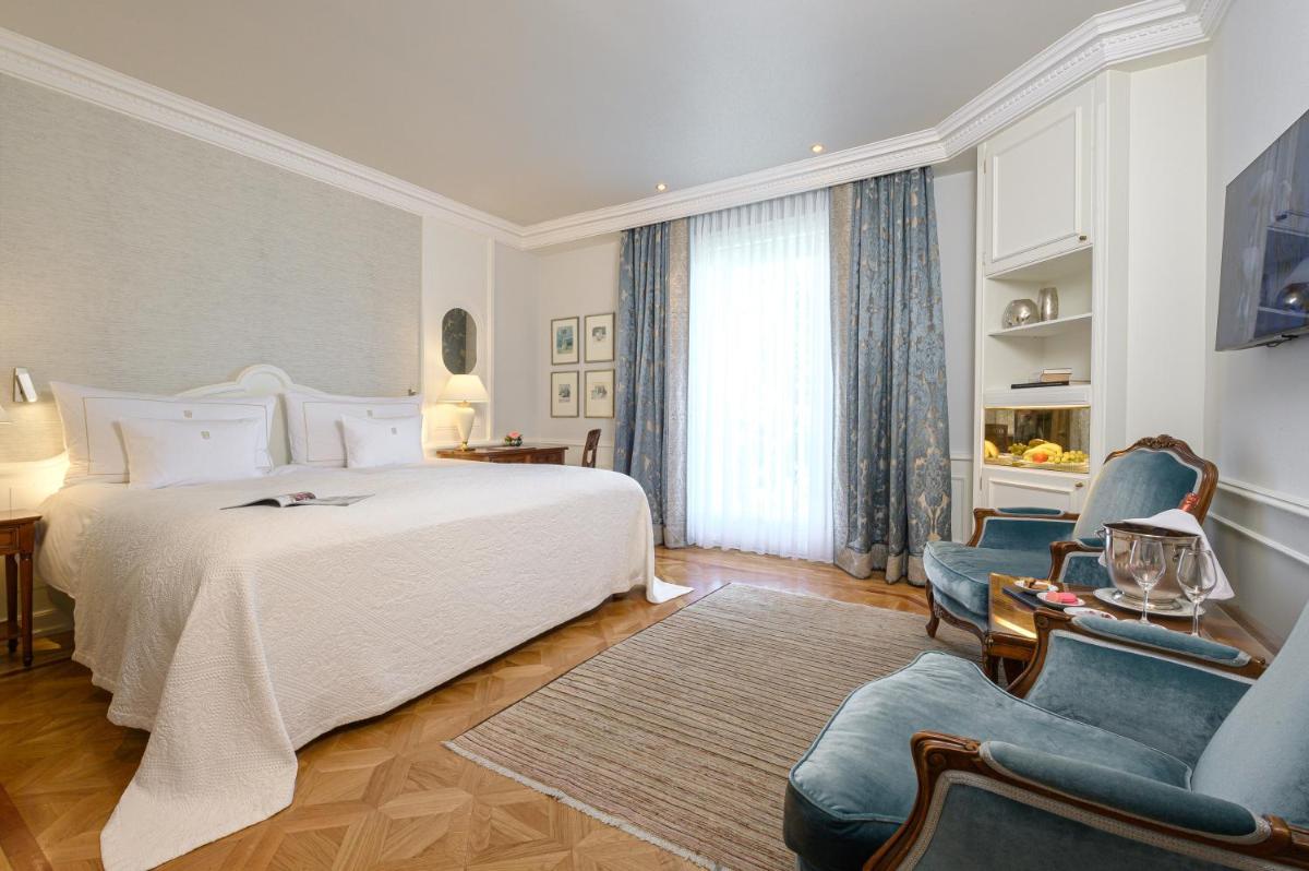 1 Schlafzimmer mit einem weißen Bett und 2 blauen Stühlen in der Unterkunft Colombi Hotel in Freiburg im Breisgau + 37 Fotos