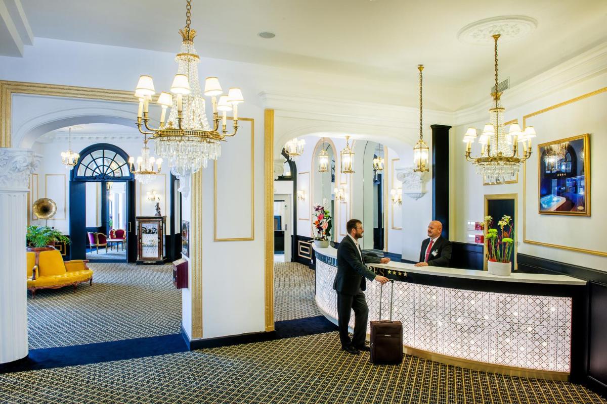 un homme debout au comptoir dans le hall de l'hôtel dans l'établissement Grand Hotel Gallia & Londres, à Lourdes