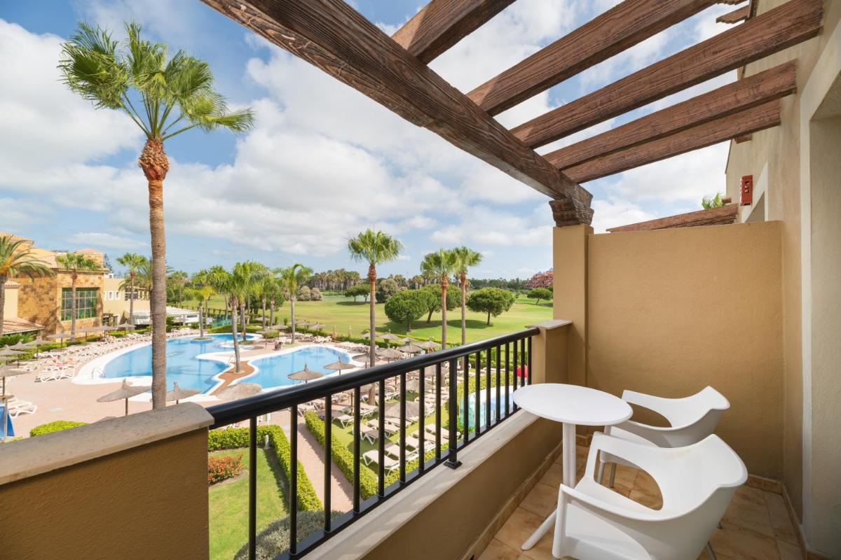 Un balcón con vista a la piscina y palmeras. en Elba Costa Ballena Beach & Thalasso Resort, en Costa Ballena 53 fotos más