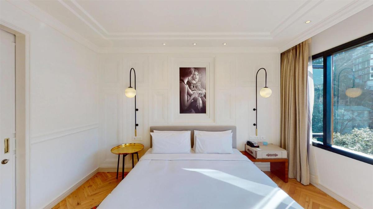 a bedroom with a large white bed and a window at Radisson Hotel Shimla in Shimla