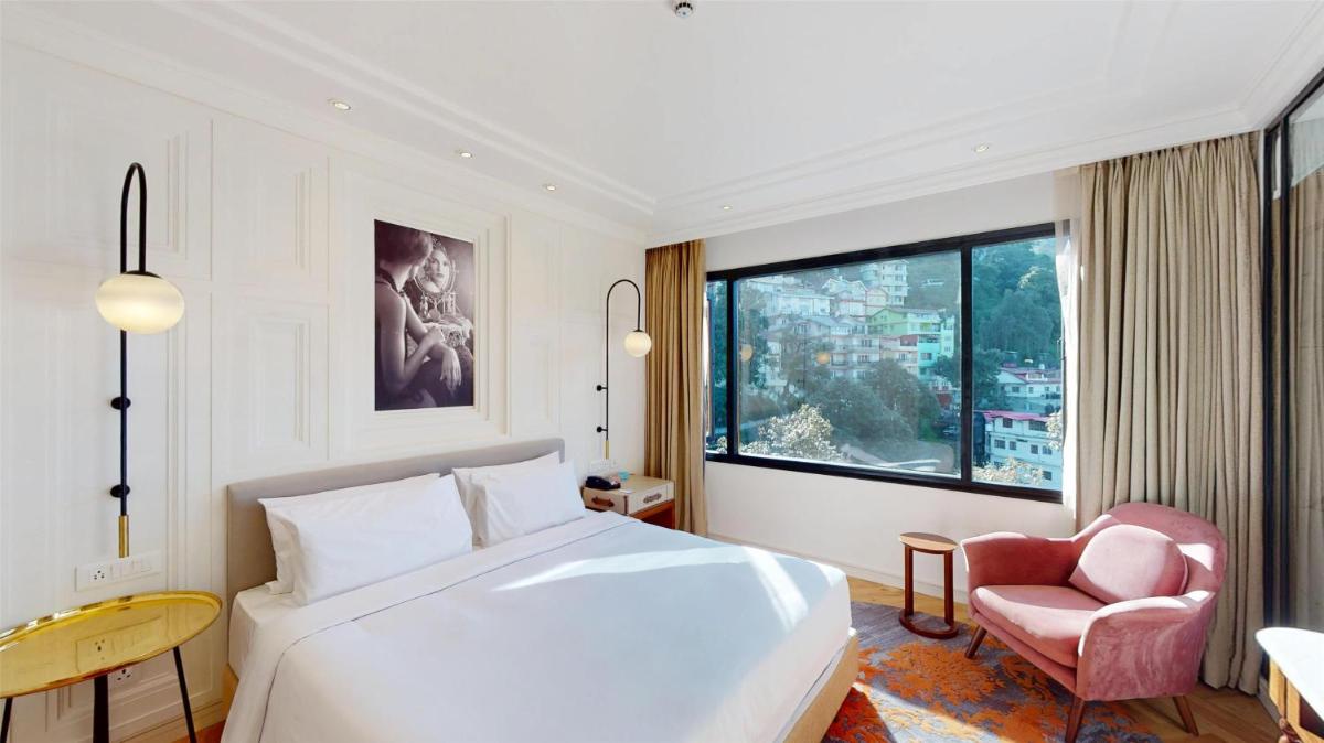 a bedroom with a white bed and a chair and a window at Radisson Hotel Shimla in Shimla +76 photos
