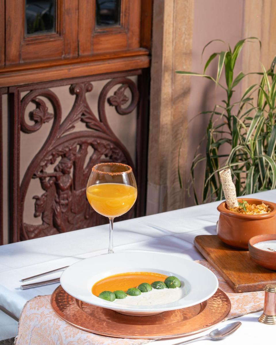 a glass of wine and a plate of food on a table at Haveli Dharampura & Golden Haveli- UNESCO awarded Boutique Heritage Hotel in New Delhi a glass of wine and a plate of food on a table at Haveli Dharampura & Golden Haveli- UNESCO awarded Boutique Heritage Hotel in New Delhi
