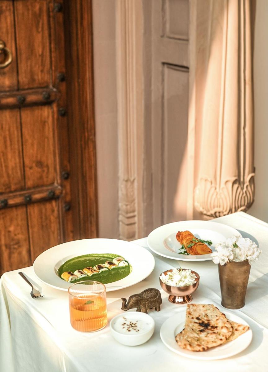 a white table with plates of food on it at Haveli Dharampura & Golden Haveli- UNESCO awarded Boutique Heritage Hotel in New Delhi a white table with plates of food on it at Haveli Dharampura & Golden Haveli- UNESCO awarded Boutique Heritage Hotel in New Delhi