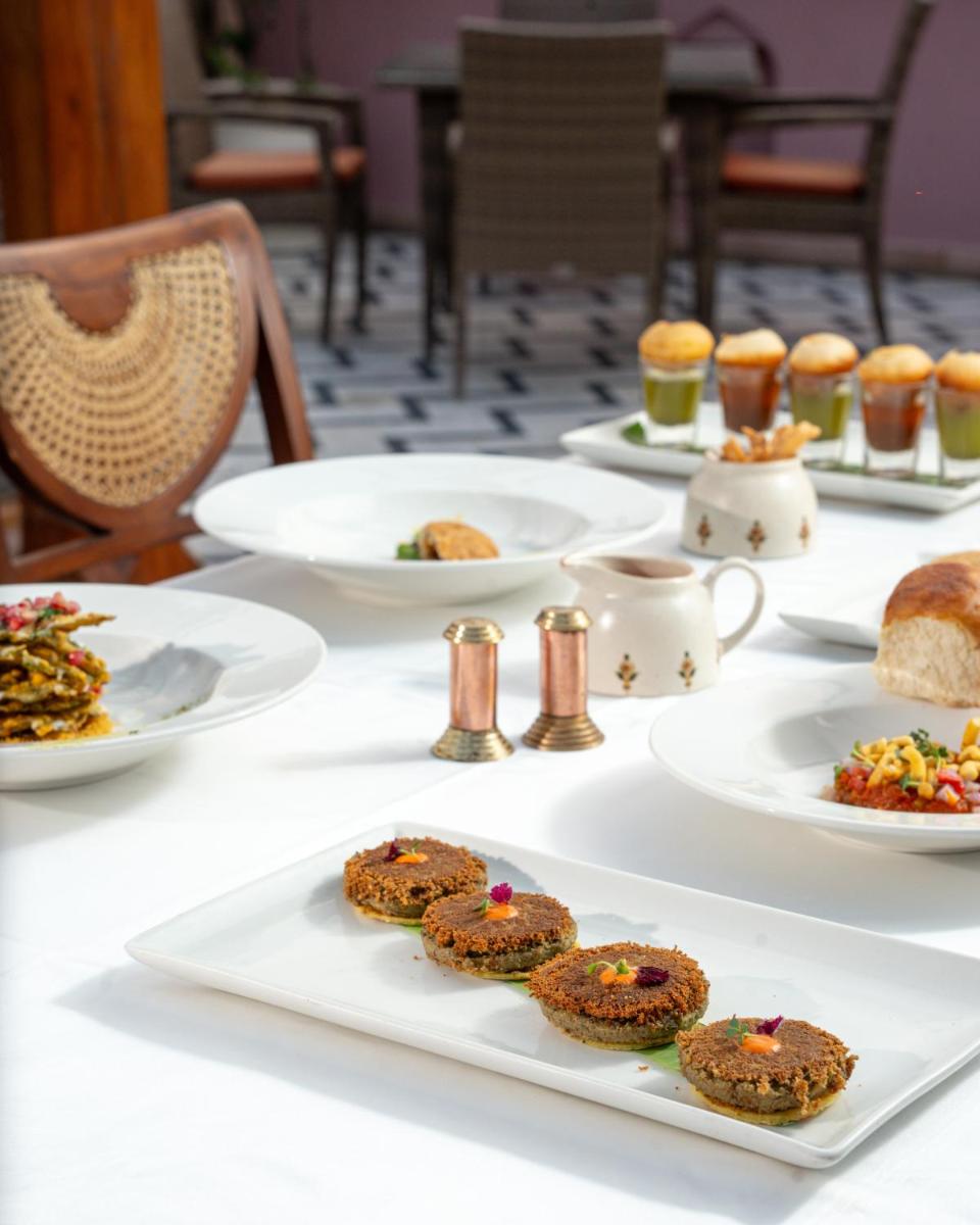 a white table with plates of food on it at Haveli Dharampura & Golden Haveli- UNESCO awarded Boutique Heritage Hotel in New Delhi a white table with plates of food on it at Haveli Dharampura & Golden Haveli- UNESCO awarded Boutique Heritage Hotel in New Delhi