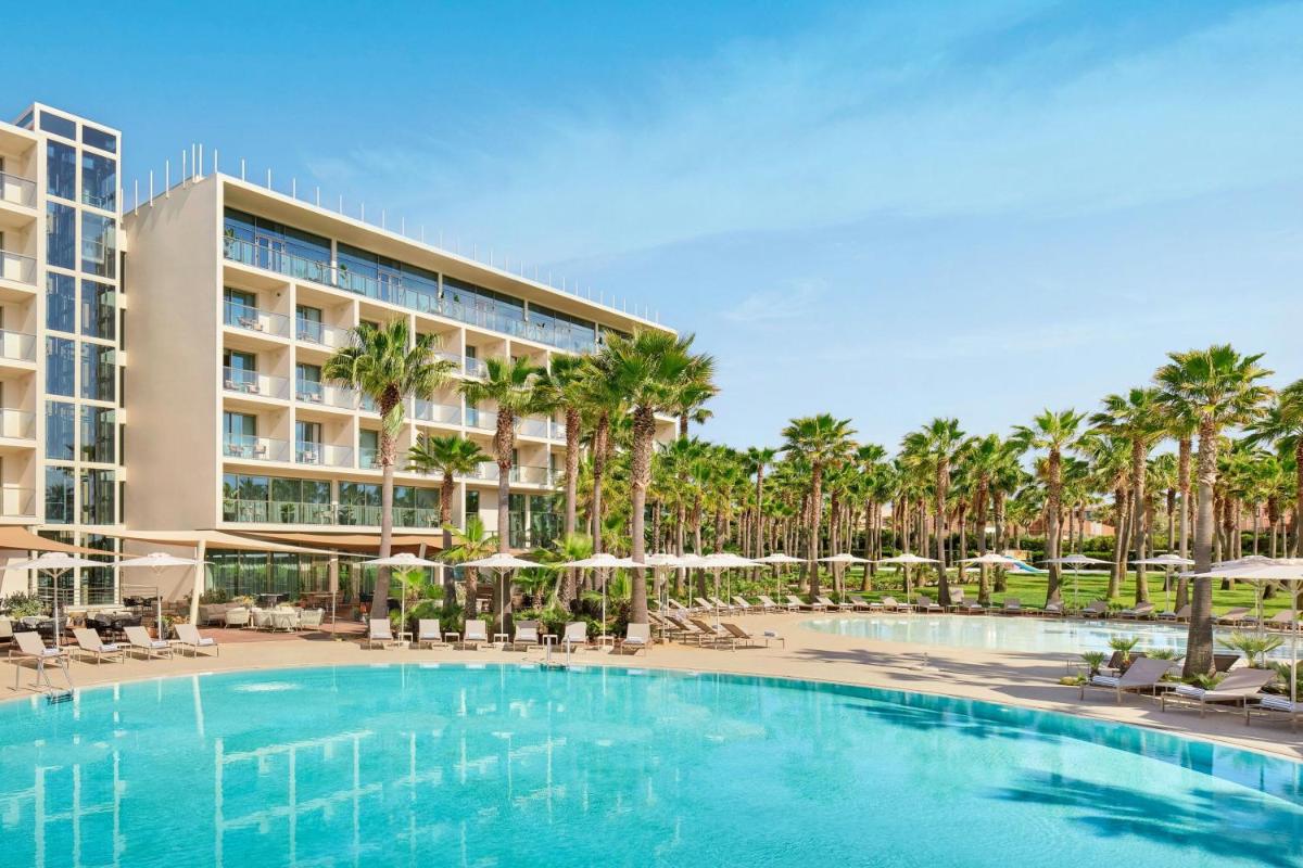 uma piscina em frente a um hotel com palmeiras em Algarve Marriott Salgados Golf Resort & Spa em Albufeira mais 62 fotografias