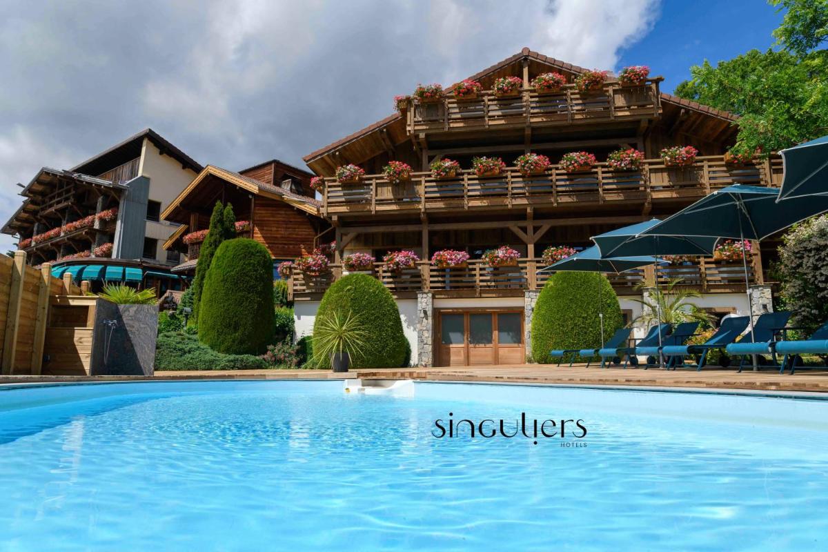 un hôtel avec une piscine devant un immeuble dans l'établissement Hôtel-Restaurant Les Bas-Rupts, Singuliers Hôtel, à Gérardmer