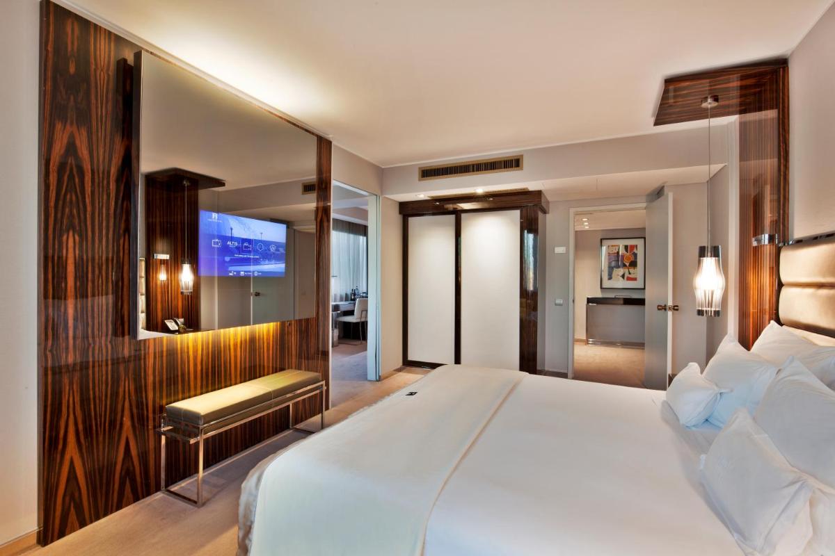 um quarto com uma cama grande e uma TV de tela plana em Altis Grand Hotel em Lisboa