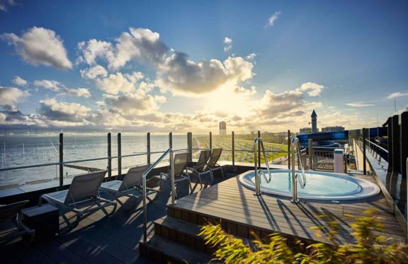 eine Terrasse mit Stühlen und einem Whirlpool mit Blick auf den Ozean in der Unterkunft Lighthouse Hotel & Spa in Büsum