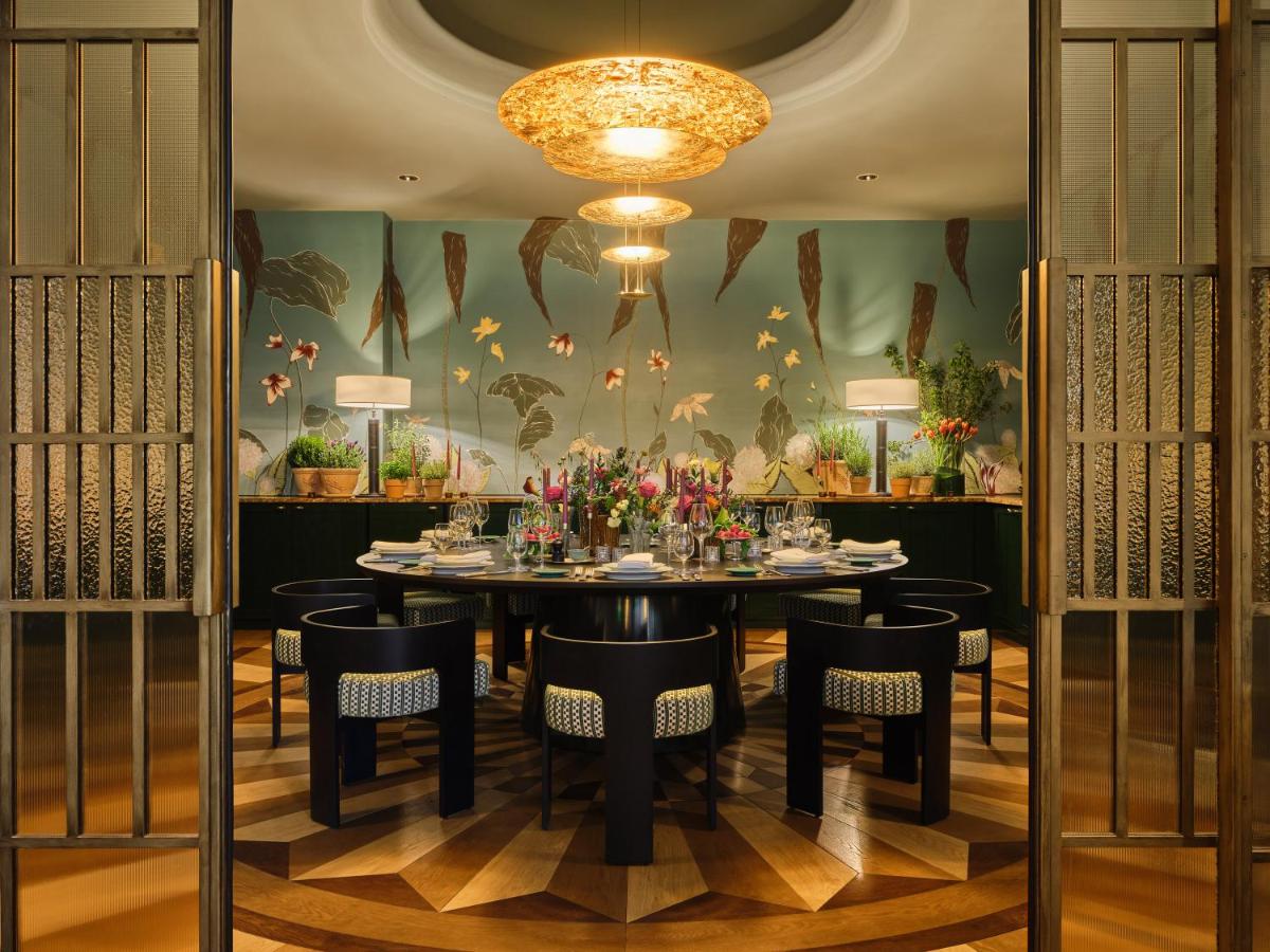 ein Esszimmer mit Tisch und Stühlen und einem Kronleuchter in der Unterkunft Rocco Forte The Charles Hotel in München ein Esszimmer mit Tisch und Stühlen und einem Kronleuchter in der Unterkunft Rocco Forte The Charles Hotel in München