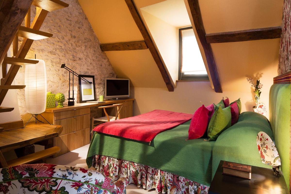 - une chambre dotée d'un lit avec des oreillers verts et rouges dans l'établissement Hotel De France, à Angerville