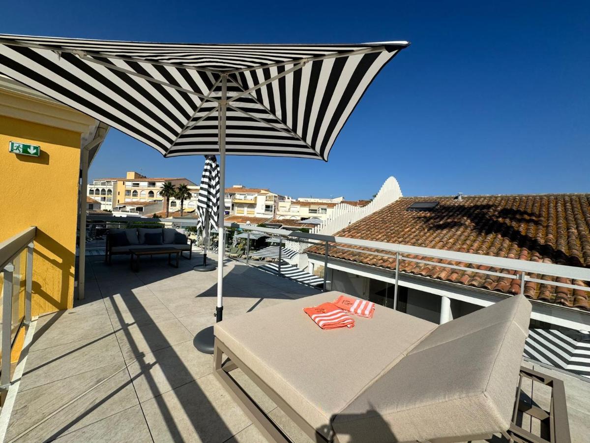 un patio avec un parasol noir et blanc sur un balcon dans l'établissement Hôtel Eve Cap d'agde Village Naturiste, au Cap d'Agde