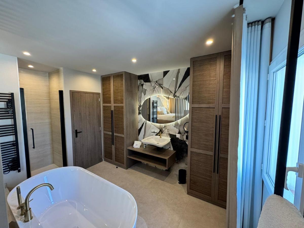 une salle de bains avec baignoire et grand miroir dans l'établissement Hôtel Eve Cap d'agde Village Naturiste, au Cap d'Agde