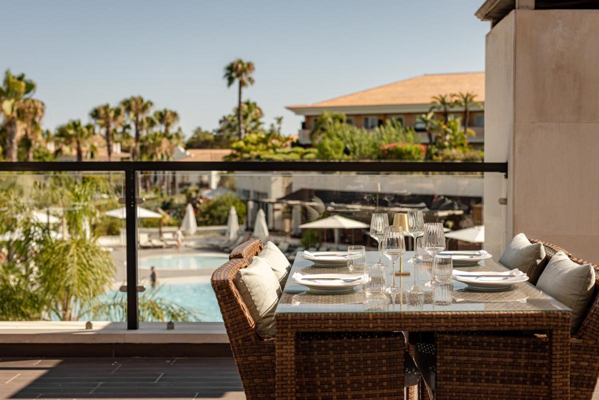 uma mesa com pratos e copos de vinho num pátio em Wyndham Grand Algarve na Quinta do Lago