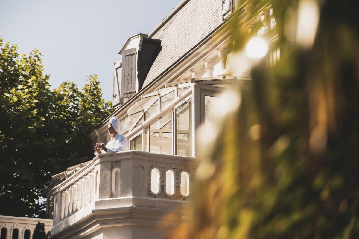 une personne assise sur le balcon d'un immeuble dans l'établissement Parc Victoria Hôtel, à Saint-Jean-de-Luz