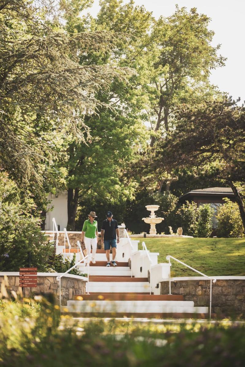 deux personnes descendant des escaliers dans un parc dans l'établissement Parc Victoria Hôtel, à Saint-Jean-de-Luz
