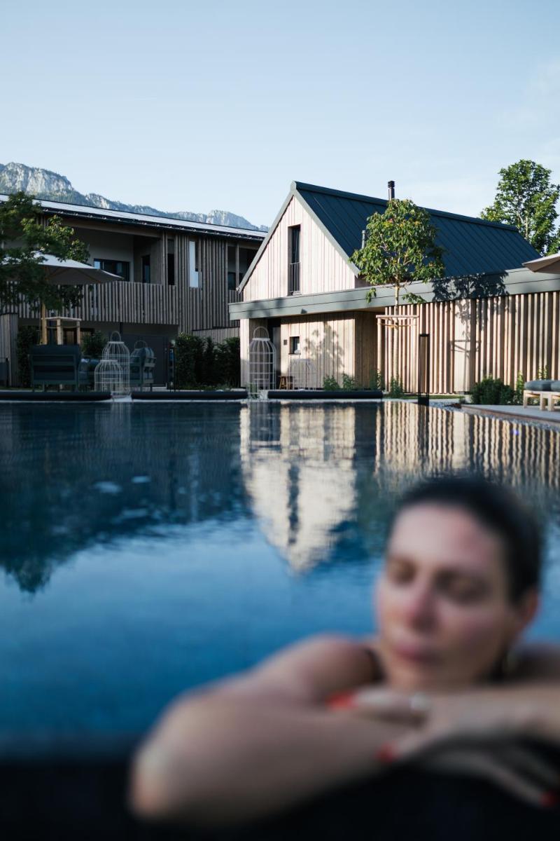 eine Frau sitzt vor einem Swimmingpool in der Unterkunft Agrad Chalets in Aschau im Chiemgau