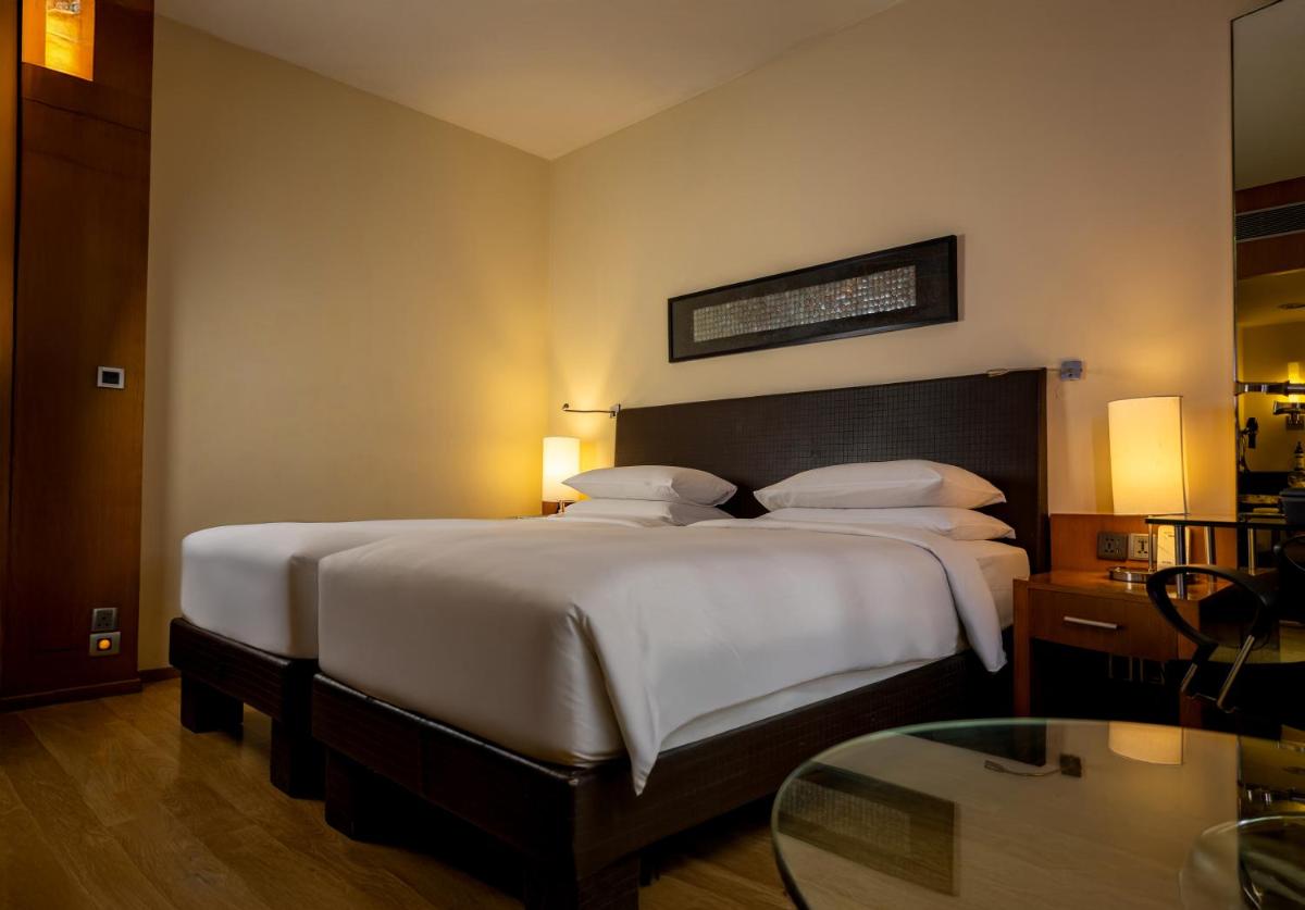 a bedroom with a large bed with white sheets and pillows at Hyatt Hyderabad Gachibowli in Hyderabad