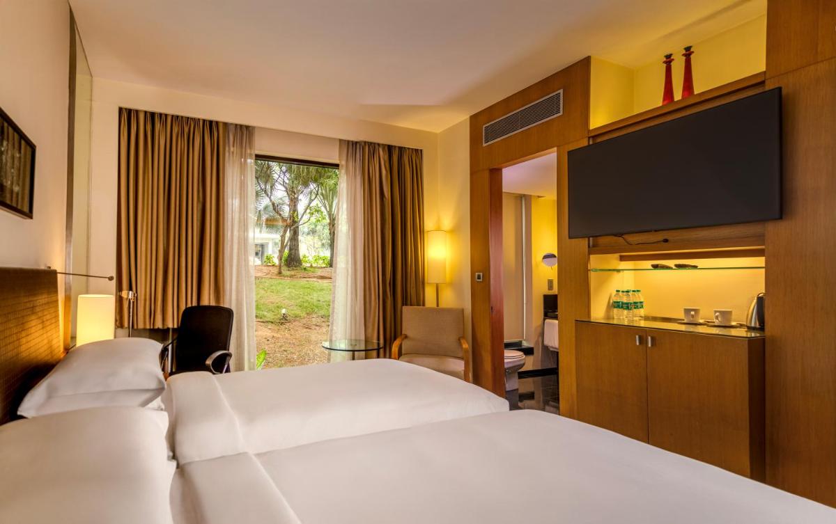 a hotel room with two beds and a flat screen tv at Hyatt Hyderabad Gachibowli in Hyderabad