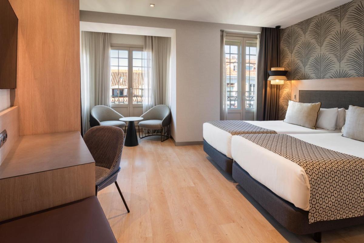una habitación de hotel con dos camas y una mesa en Catalonia Atocha, en Madrid