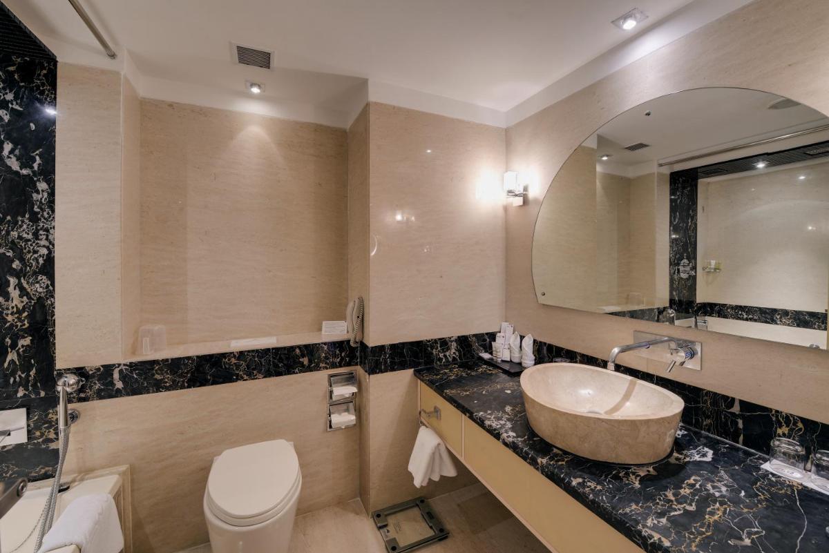 a bathroom with a sink and a toilet and a mirror at The Zuri Whitefield Bengaluru in Bengaluru a bathroom with a sink and a toilet and a mirror at The Zuri Whitefield Bengaluru in Bengaluru