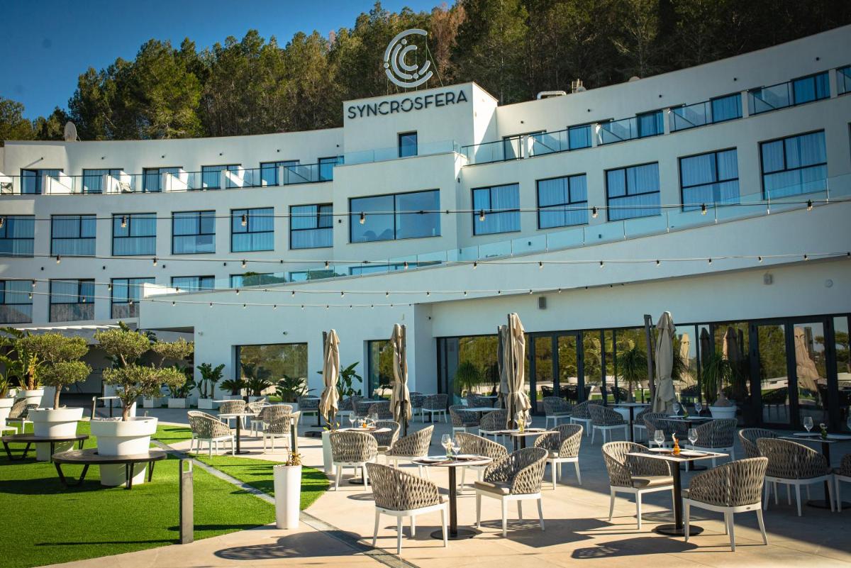 Un hotel con mesas y sillas frente a un edificio. en Syncrosfera Fitness & Spa Health Hotel Boutique, en Pedreguer