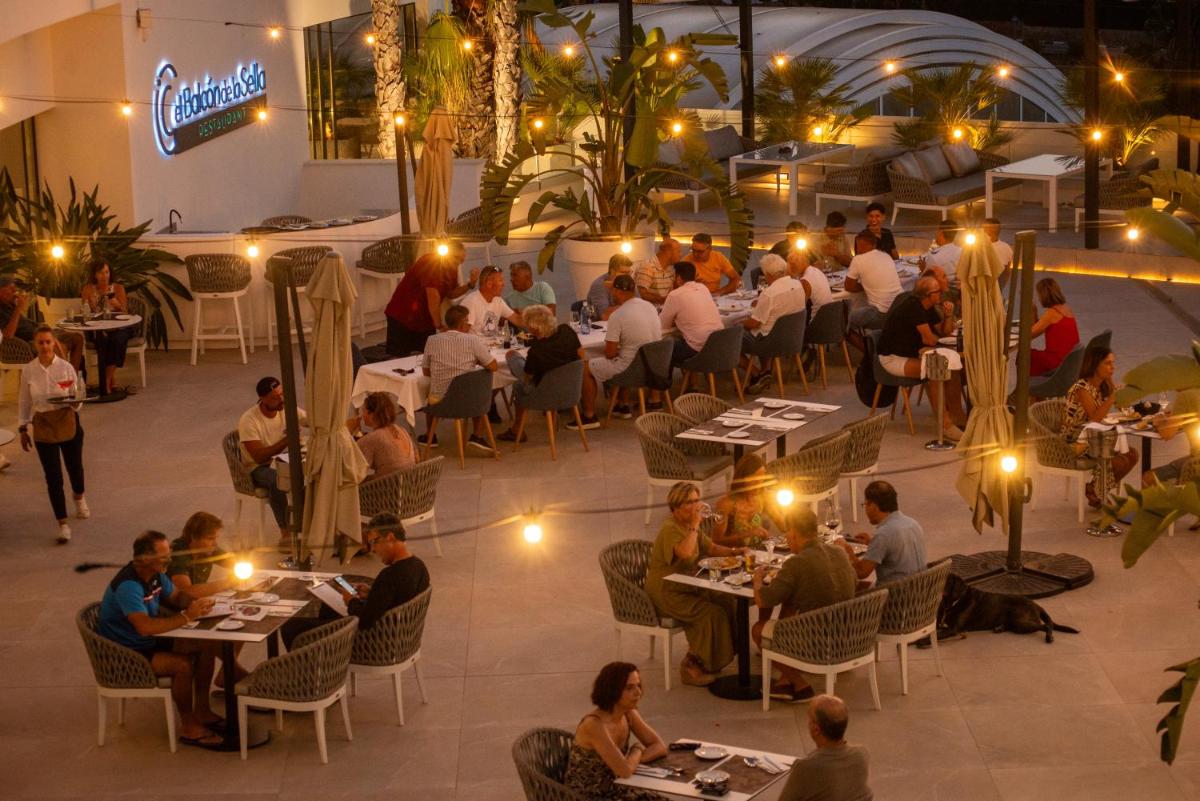 un grupo de personas sentadas en mesas en un restaurante en Syncrosfera Fitness & Spa Health Hotel Boutique, en Pedreguer